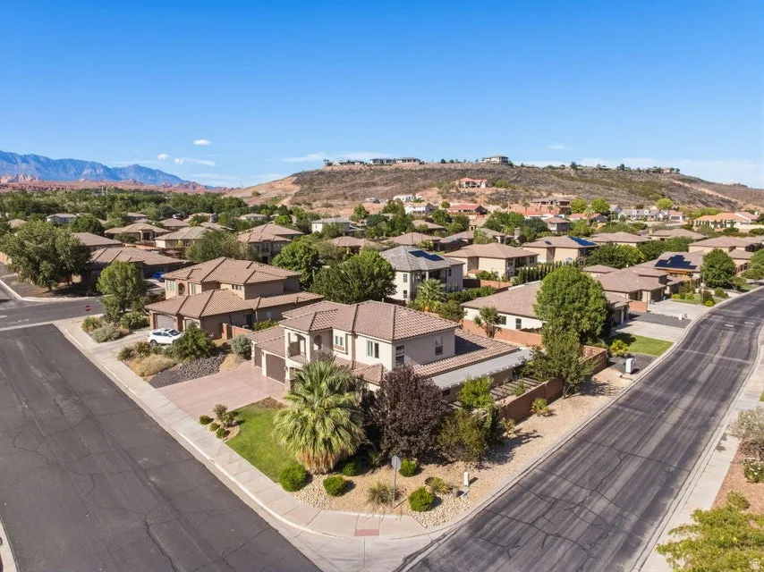 Elegant two-story residence situated on a corner lot featuring a stucco exterior, arched entryway, and professional landscaping with mature trees and drought-resistant plantings