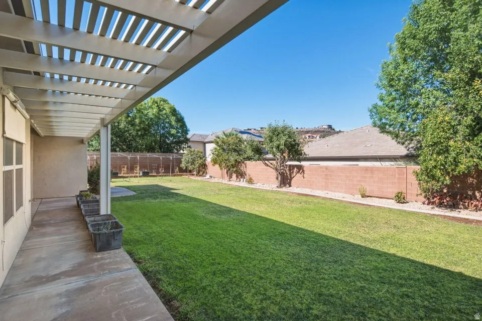 Expansive backyard featuring a manicured lawn, mature trees, and brick perimeter fencing