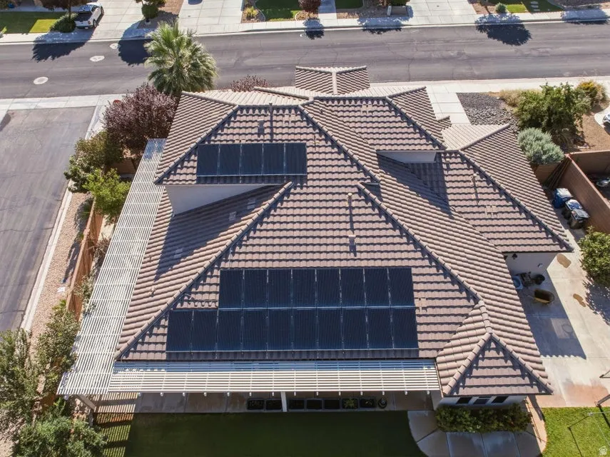 Stunning aerial view of this residence showcasing an expansive roof featuring multiple pitched sections with dark tile roofing and integrated solar panel arrays