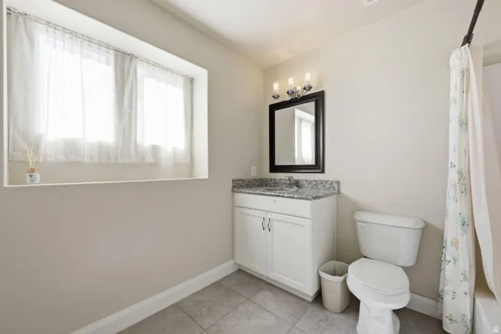 Bright and functional bathroom featuring a white vanity with dual-door cabinetry, granite-style countertop, and an integrated sink