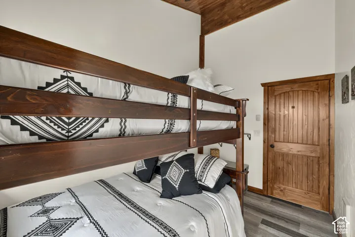 Rustic bedroom retreat featuring a wooden bunk bed frame with geometric patterned bedding, exposed beam ceiling, and wood-finish flooring