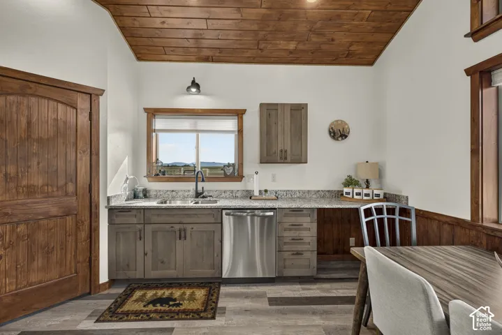 Chef's kitchen featuring custom cabinetry with wood-finish finishes, stainless steel appliances including a professional-grade refrigerator and dishwasher, granite countertops, and a large farmhouse sink with chrome faucet