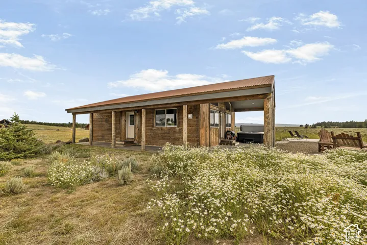 Charming rural residence featuring warm wood-finish exterior with covered front porch, expansive covered side deck, and large operable windows allowing natural light throughout