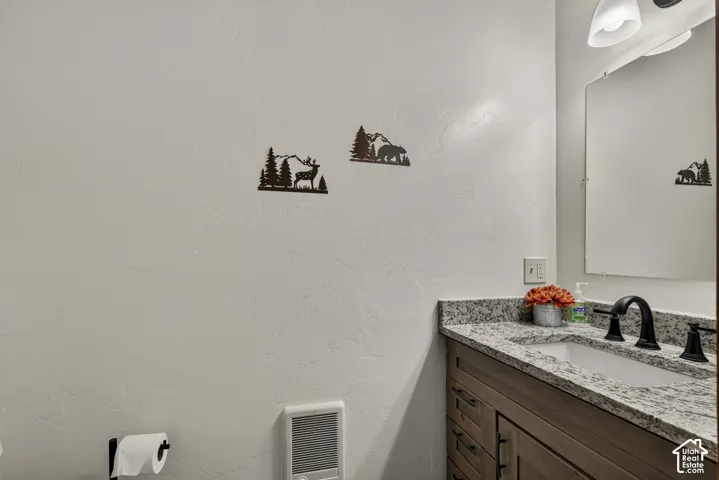 Vanity with a granite countertop, undermount sink, and matte black faucet