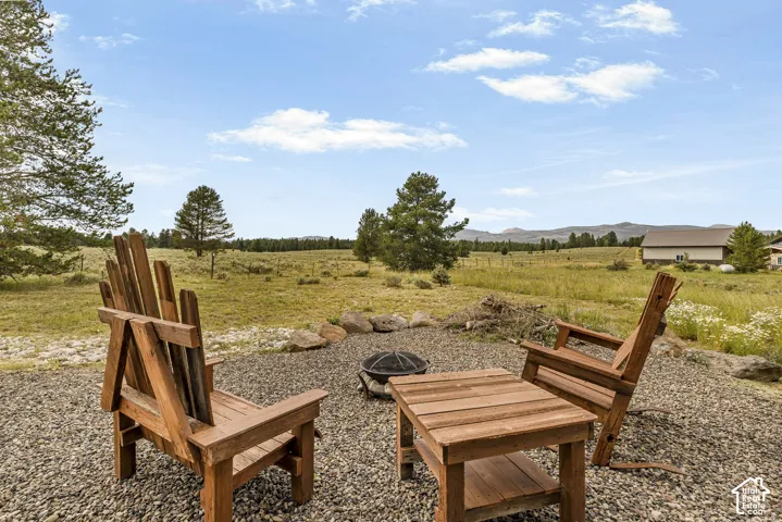 Rustic outdoor gathering space featuring custom wood Adirondack seating arranged around a fire pit on a gravel base