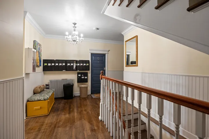 Entryway featuring wood-finish flooring, beadboard wainscoting, and a crystal chandelier