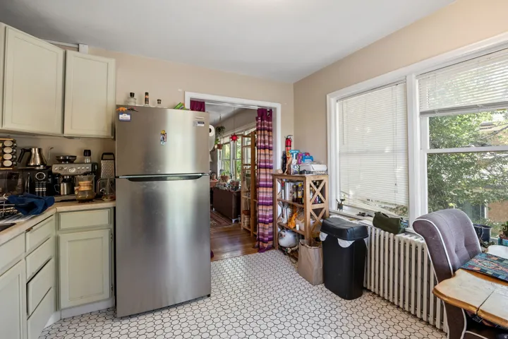 Kitchen featuring white hexagonal tile flooring, light-toned cabinetry, and a stainless steel refrigerator