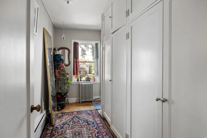 Hallway featuring extensive built-in cabinetry, wood-finish flooring, and a window with natural light