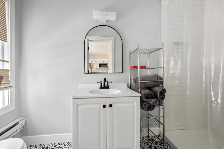 Bathroom featuring a white vanity with integrated sink, black hardware, and an arched mirror
