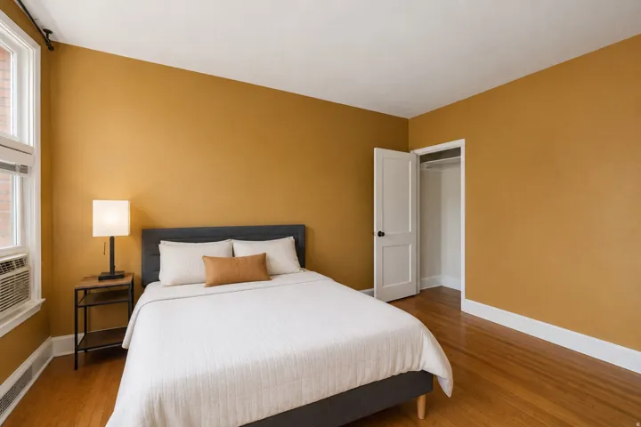 Room featuring wood-finish flooring, white trim, and a window with an integrated air conditioning unit