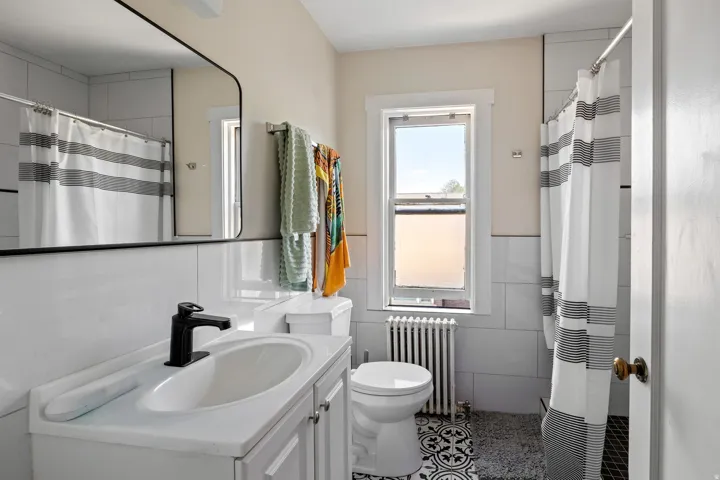 Bathroom featuring a white vanity with an integrated sink, matte black faucet, and a large black-framed rectangular mirror