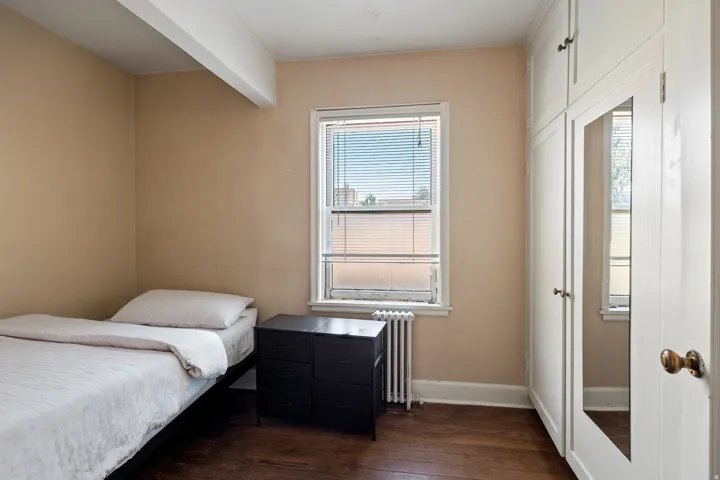 Room featuring wood-finish flooring, a window with blinds, and built-in storage cabinetry