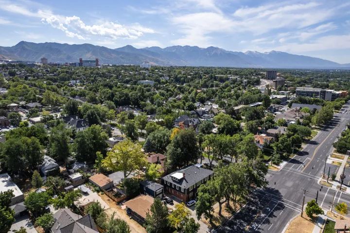Expansive neighborhood setting featuring a vibrant tree canopy, paved roadways, and a prominent mountain range in the distance