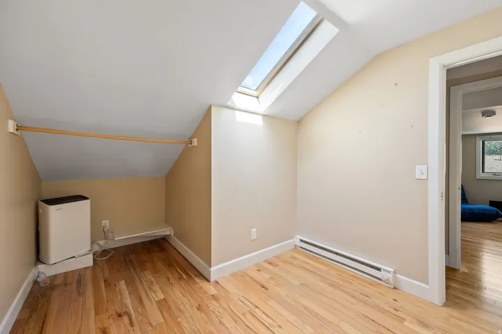 Bright interior space featuring a prominent skylight and light wood-finish flooring