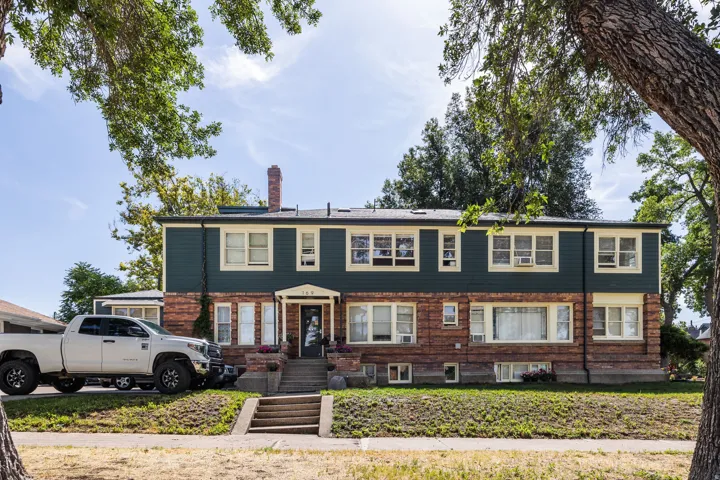 Two-story property featuring a brick lower facade and dark green siding upper facade
