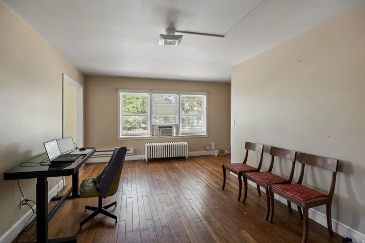 Spacious room featuring wood-finish flooring, light-toned walls, and multiple windows