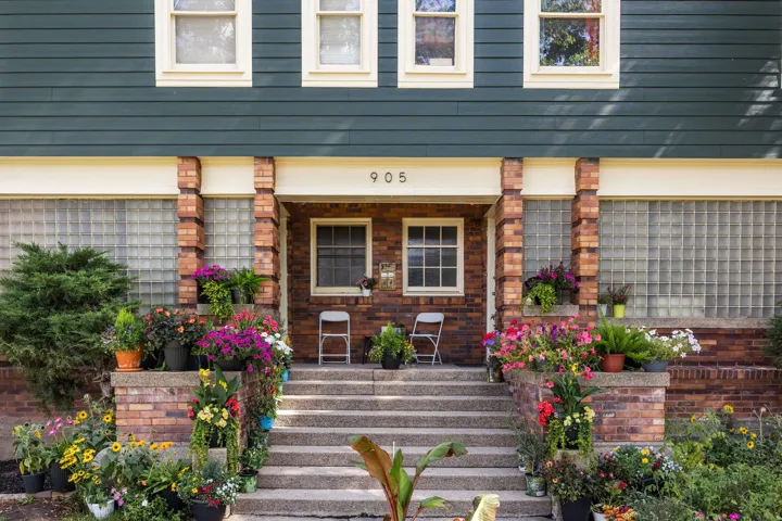 Brick and plank siding exterior featuring a prominent entry with concrete steps and brick pillars