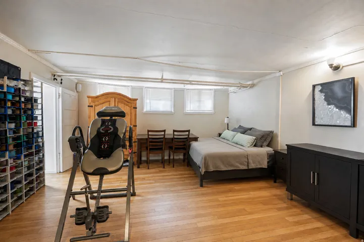 Spacious room featuring wood-finish flooring, a built-in storage system, and two windows