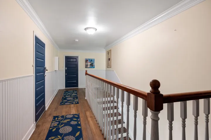 Hallway featuring wood-finish flooring, beadboard wainscoting, and crown molding