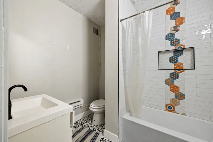 Bathroom featuring a white subway tile shower surround with an accent band of patterned hexagonal tiles