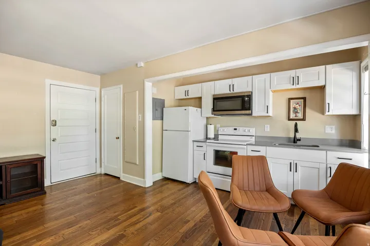 Open-concept kitchen featuring white shaker cabinetry, stainless steel microwave, integrated dishwasher, and a black faucet