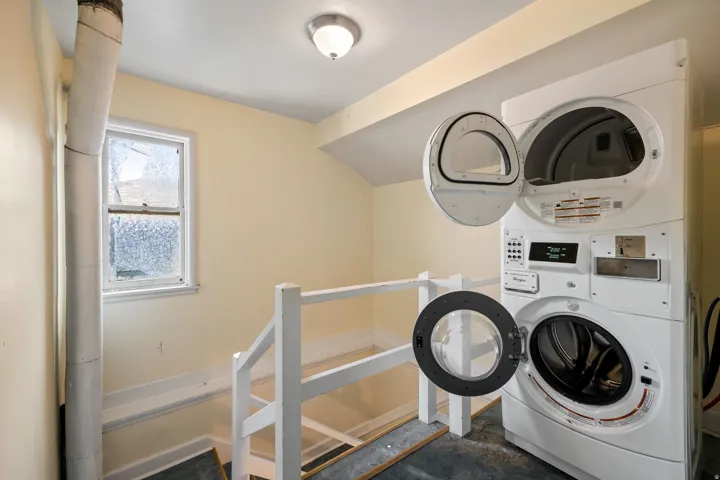 Dedicated laundry area featuring a stacked washer and dryer unit, overhead flush mount lighting, and a window