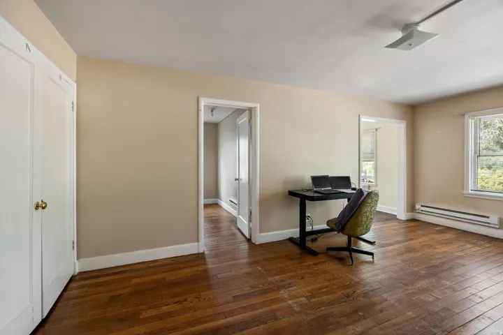 Hardwood flooring throughout this room featuring neutral wall tones, white trim, and two white bi-fold closet doors