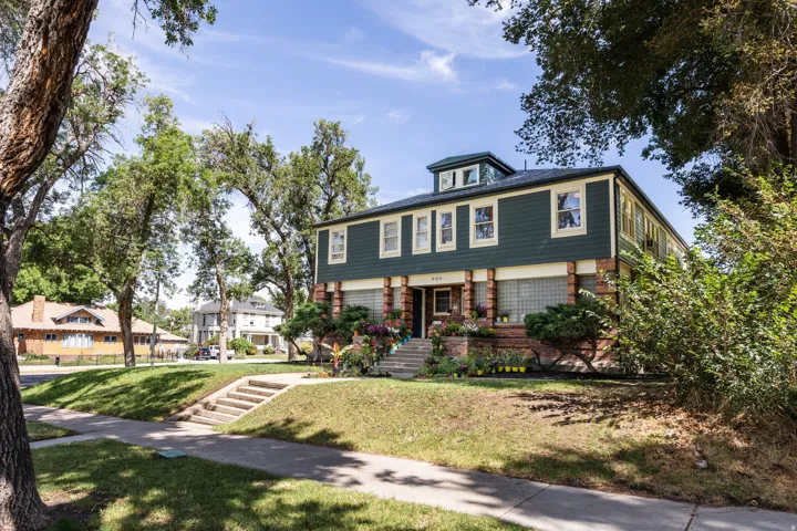 Two-story dwelling featuring a dark green facade with light trim and a prominent central dormer