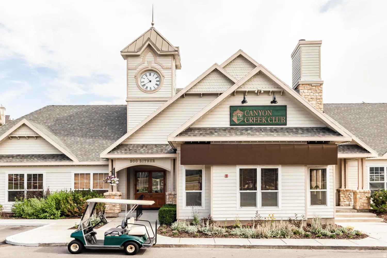 Charming Colonial-style clubhouse featuring a prominent clock tower, white horizontal siding, and a covered entry portico