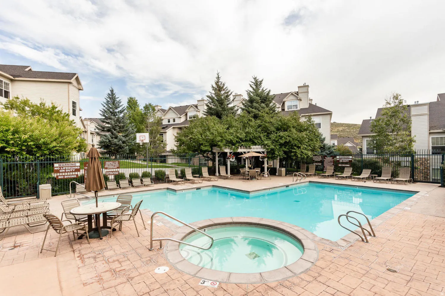 Outdoor pool area featuring a rectangular swimming pool and circular spa with stone coping