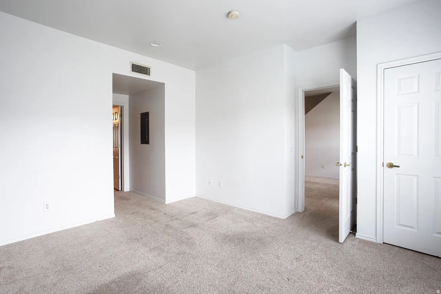 Spacious bedroom featuring neutral carpet flooring, white six-panel closet doors, and multiple entry points