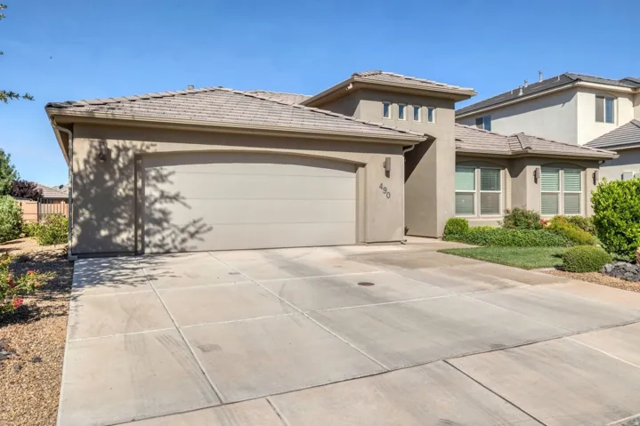 Spacious driveway featuring a wide concrete apron with clean, geometric scoring patterns and a three-car garage with a neutral-toned sectional door