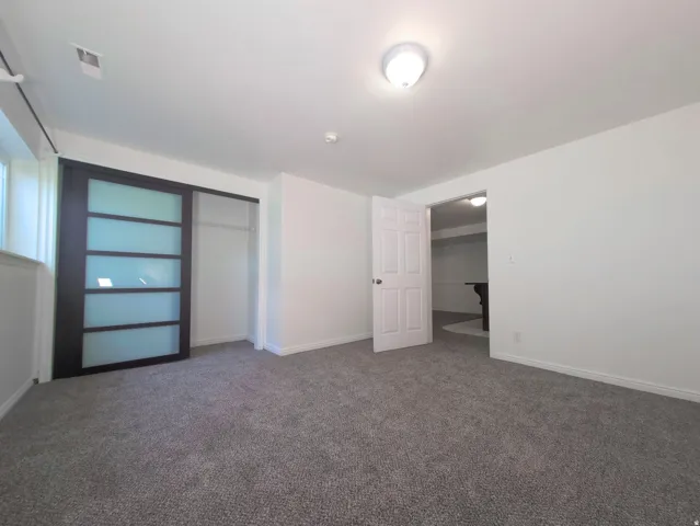 Spacious bedroom featuring neutral carpeting, recessed ceiling lighting, and multiple closet options including a walk-in closet with shelving