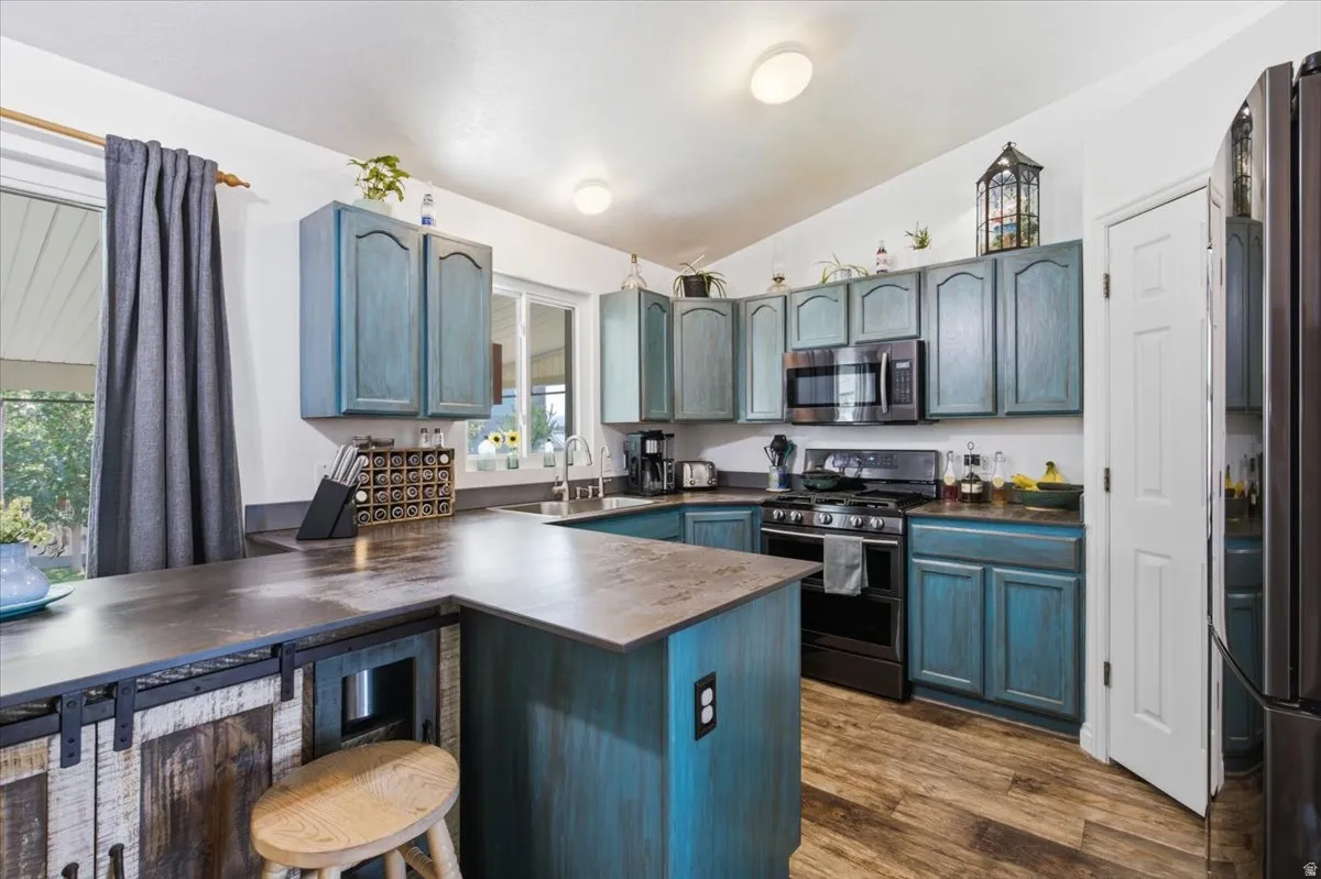 Chef's kitchen featuring custom cabinetry in soft blue-gray tones with arched glass-front doors, stainless steel appliances including a gas range, and a generously sized island with wood-finish countertops and seating