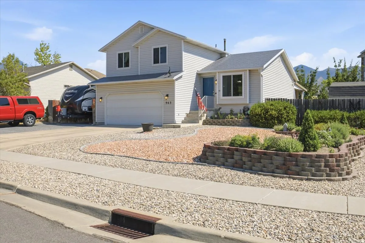 Two-story residence featuring light gray siding, a two-car garage, and a gravel driveway