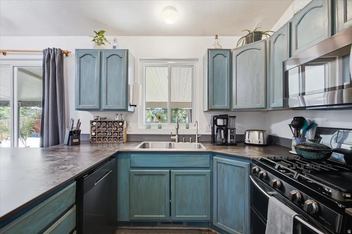 Contemporary kitchen featuring custom cabinetry with soft blue-gray finish, stainless steel gas range with multiple burners, quartz countertops, and an undermount sink with chrome faucet