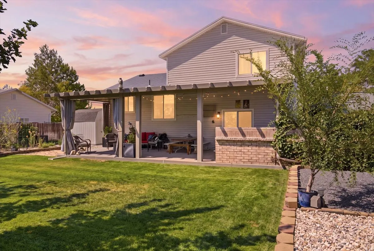 Spacious backyard retreat featuring a manicured lawn, mature landscaping, and a covered patio with integrated seating areas