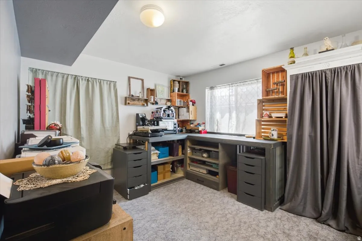 Dedicated craft and hobby room featuring expansive built-in cabinetry with ample storage, a generous work surface with integrated shelving, and abundant natural light from multiple windows