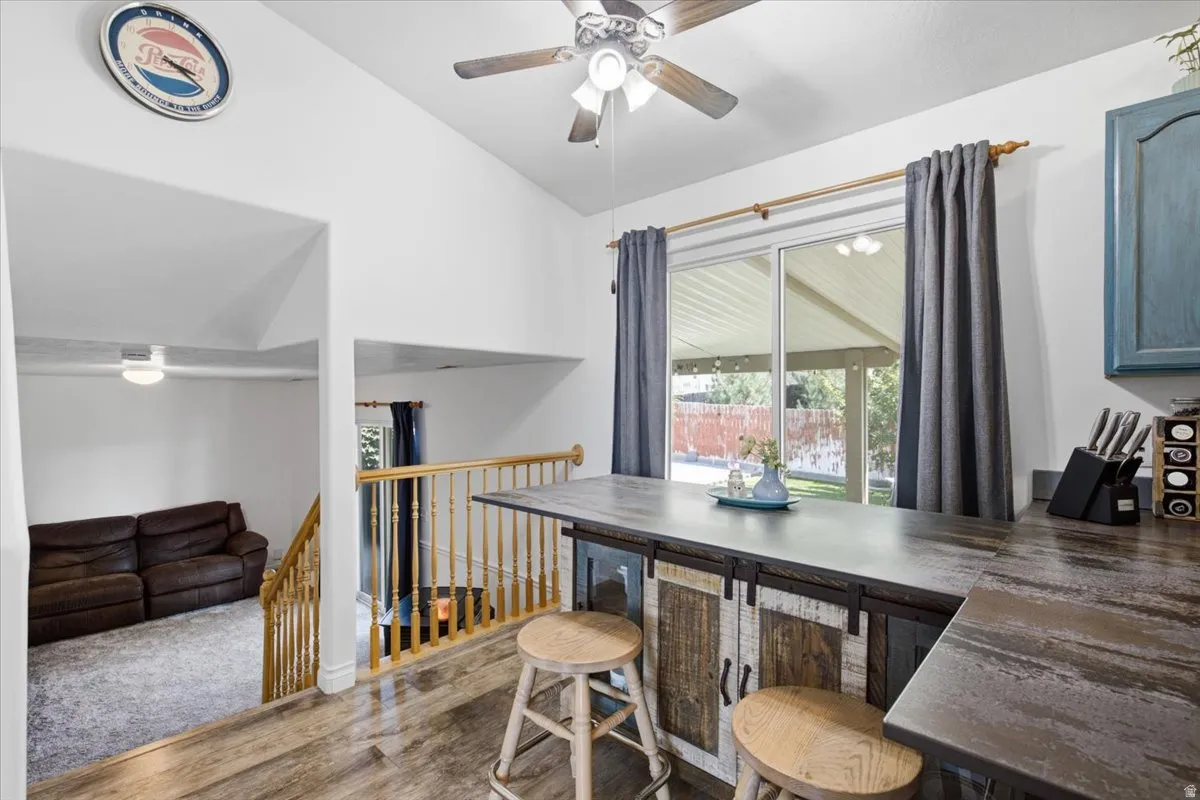 Open-concept living space featuring hardwood flooring, a functional work counter with seating, and abundant natural light from sliding glass doors