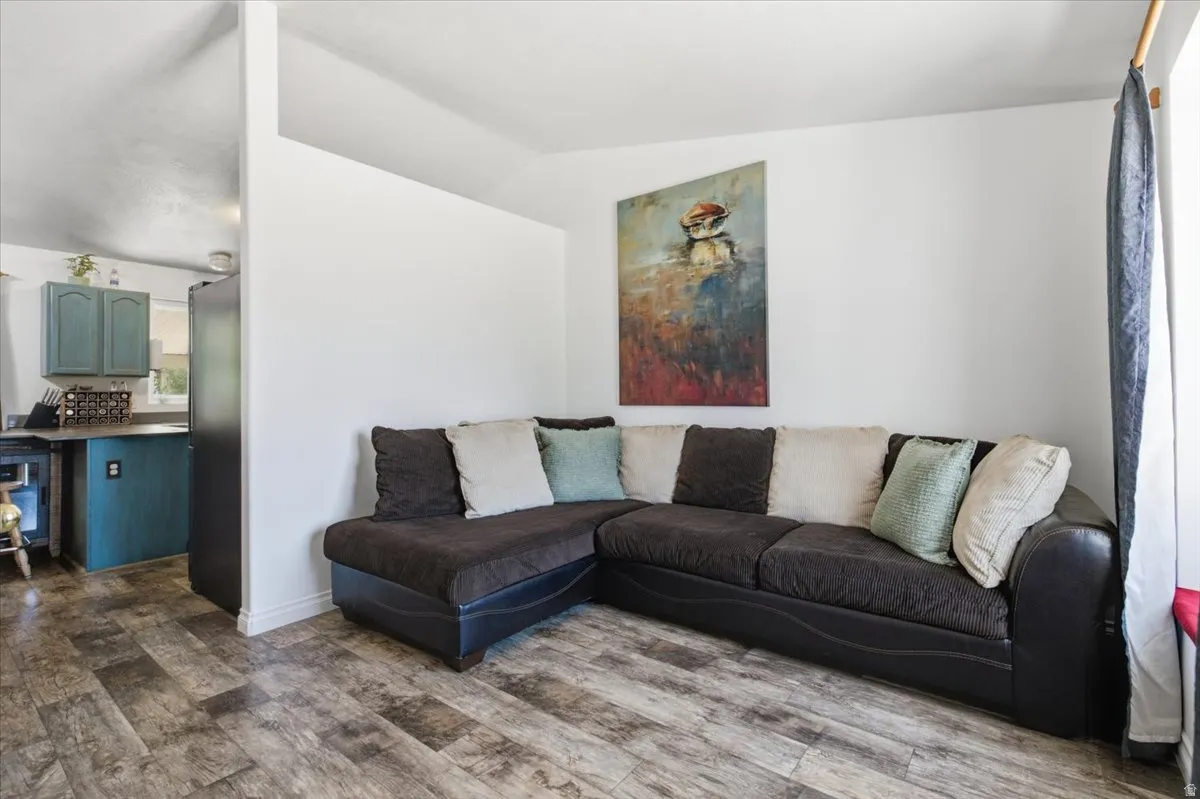 Spacious living area featuring a sectional sofa arrangement with decorative throw pillows, wood-finish flooring, and white walls