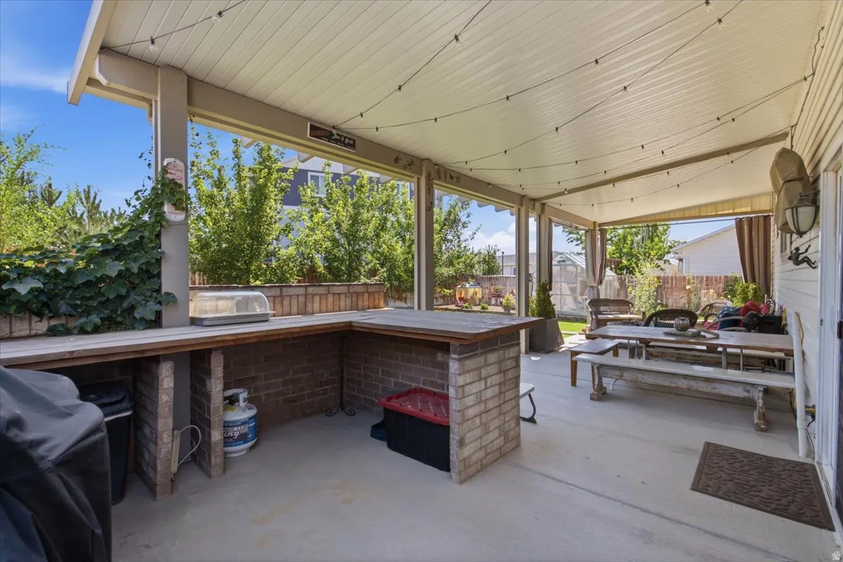 Covered patio with polished concrete flooring and wood-beamed ceiling featuring recessed lighting