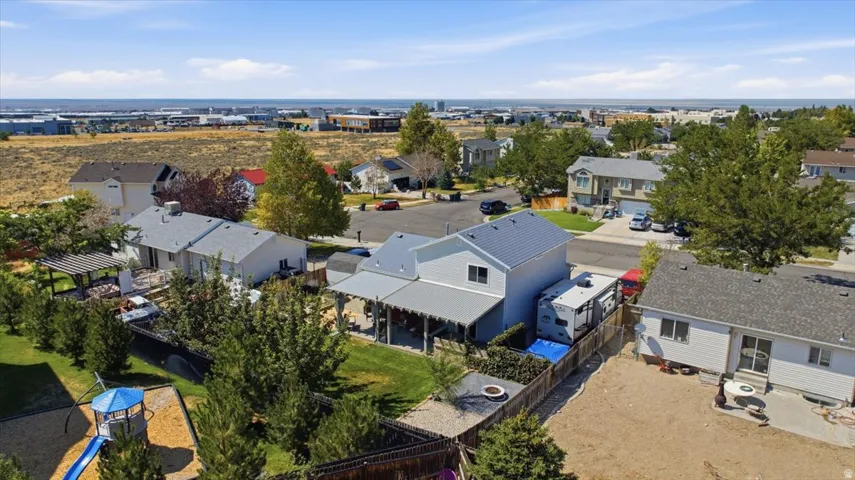 Spacious suburban property featuring a two-story residence with light gray siding and a gray metal roof, complemented by a covered patio area