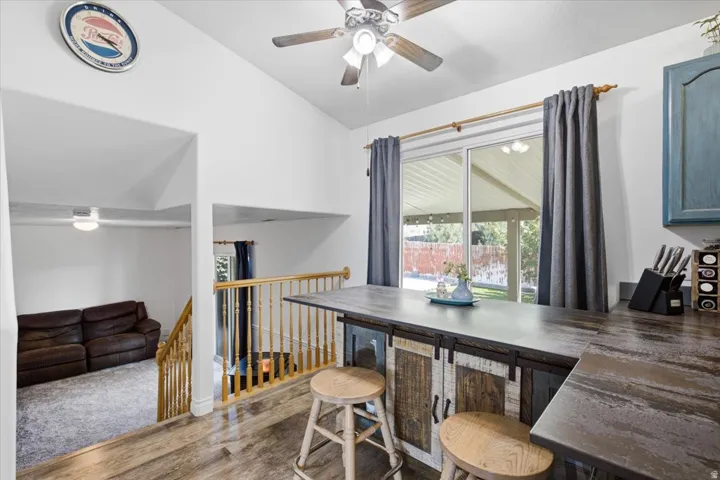 Open-concept living space featuring hardwood flooring, a functional work counter with seating, and abundant natural light from sliding glass doors