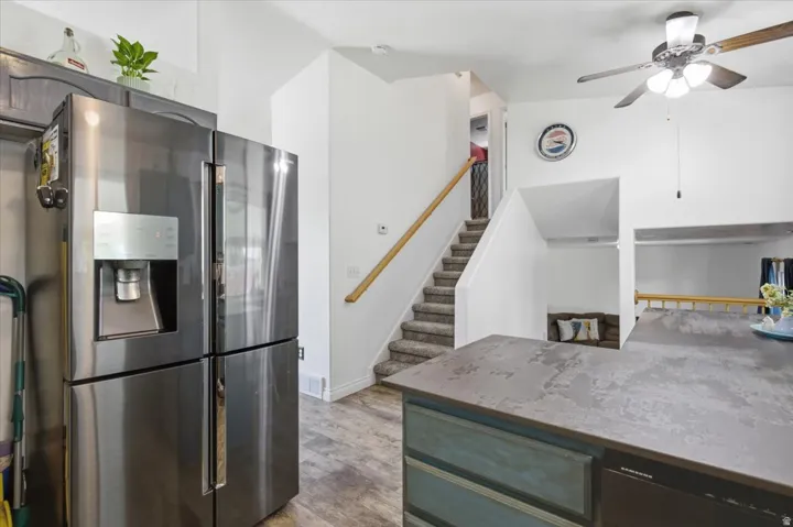 Modern kitchen featuring stainless steel French-door refrigerator with ice and water dispenser, gray quartz countertops, and a teal-finished island with seating