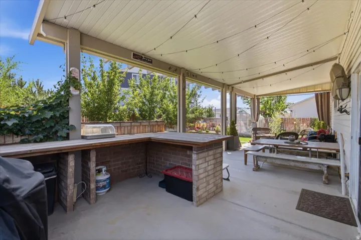 Covered patio with polished concrete flooring and wood-beamed ceiling featuring recessed lighting