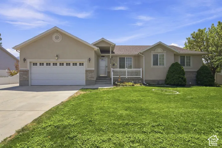 Welcoming ranch-style home featuring a two-car attached garage with paneled doors, stucco exterior in neutral tones, and a front-facing covered entry with decorative railings