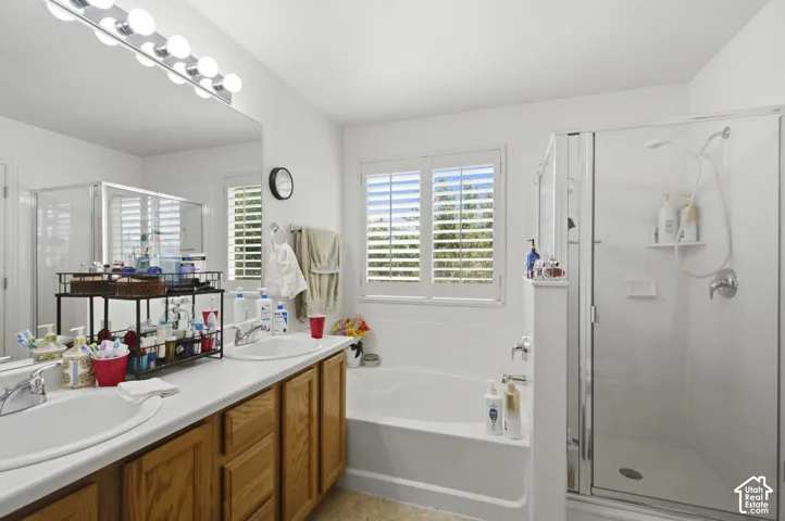 Spa-inspired primary bathroom featuring a wood-finish vanity with dual sinks, white quartz countertops, and chrome fixtures