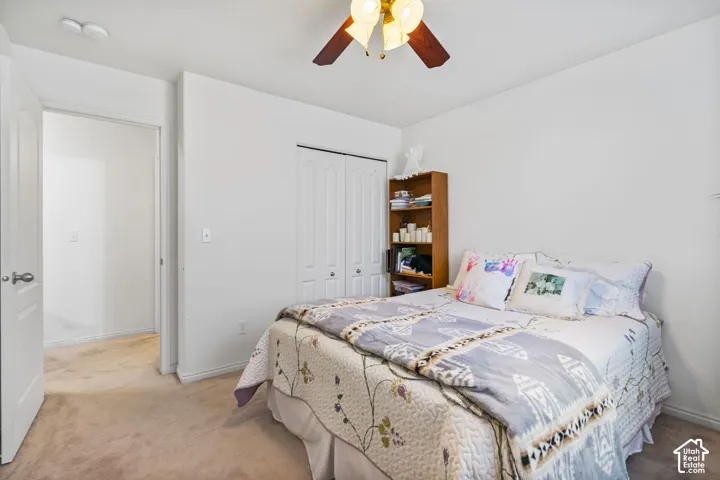 Comfortable secondary bedroom featuring ceiling fan with integrated lighting, and ample natural light from window