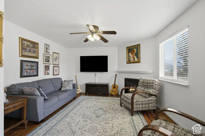 Comfortable living room featuring a blue upholstered sofa, wood-finish side table, and patterned accent chairs arranged around a fireplace with gas insert