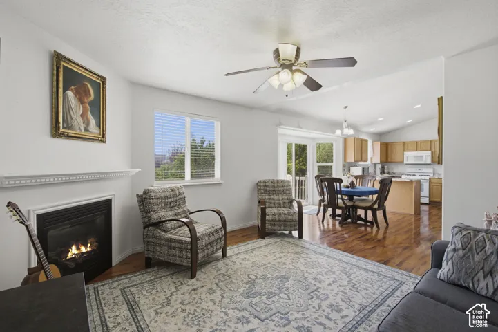 Bright and open living space featuring a gas fireplace with black surround, ceiling fan with integrated lighting, and bamboo flooring